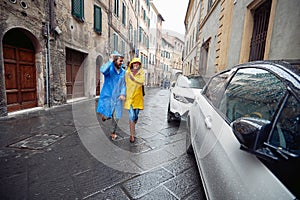 A young couple in love is enjoying a walk the city in raincoats during a rainy day. Walk, rain, city, relationship