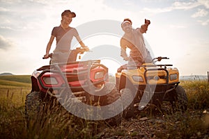 A young couple in love enjoys a scenery while riding quads in the nature. Riding, relationship, nature, activity photo