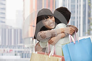 Young couple in love going shopping and embracing each other with colorful shopping bags in the street, Beijing, China