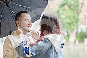 Young couple in love happy under an umbrella in the rain in the summer.