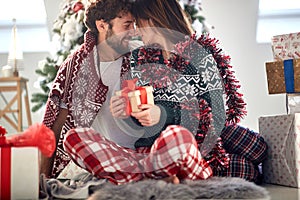 A young couple in love has moments of closeness giving Xmas presents at home. Christmas, relationship, love, together
