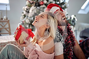 A young couple in love having fun giving Xmas presents at home. Christmas, relationship, love, together