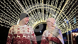 Young couple in love having fun under holiday winter illumination at night, lovers