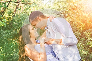 Young couple in love holding hands, hugging and smiling in trees tunnel. Men tilted the woman. Outside portrait of young couple