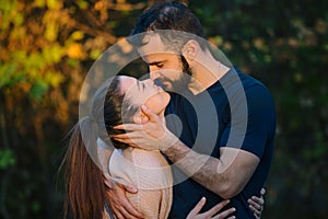 Young couple in love hugging and kissing in the Park. They are illuminated by a ray of sunlight. In the background autumn forest