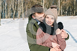 Young couple in love hugging in the park in winter sunny day