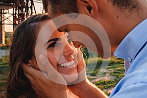 Young couple in love hugs on sunset amidst a bridge under construction. Man holds woman`s face in his hands. Outdoor portrait