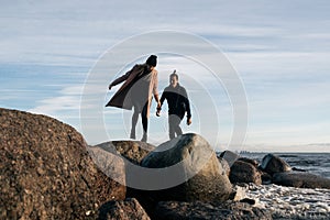 Young couple in love jumping over stones in water. Happy lovers have fun on the beach.