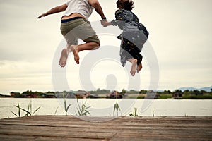 Young couple in love jumping on the shore of the lake