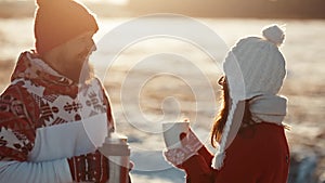 Young couple in love kiss in first snowy winter day and drink tea. Happiness, relationship concept. Happy people smiling