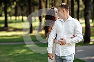 young couple in love is kissing in the park on a summer day. man and woman are hugging outdoors