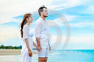 Young couple in love looking the future and holding hand together at sea beach on blue sky .happy smiling young wedding with