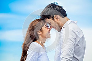 Young couple in love looking to each other and holding hand together at sea beach on blue sky .happy smiling young wedding with