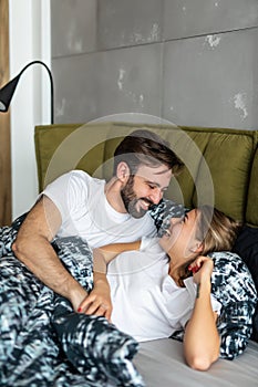 Young couple in love lying on bed. Man waking up his wife in morning