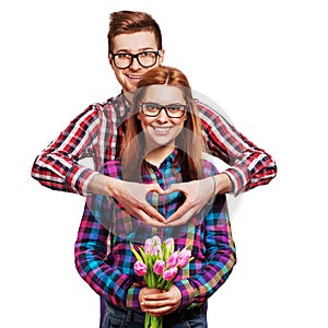 Young couple in love make a heart and hands are holding tulips.