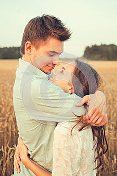 Young couple in love outdoor.Couple hugging.Young beautiful couple in love staying and kissing on the field on sunset.