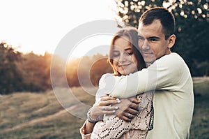 Young couple in love outdoor. They are smiling and looking at each other. evening sunlight, hugs and kisses, vintage style