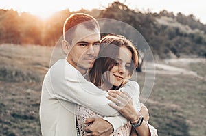 Young couple in love outdoor. They are smiling and looking at each other. evening sunlight, hugs and kisses, vintage style