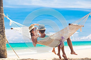 Young couple in love relaxing in a hammock by the beach