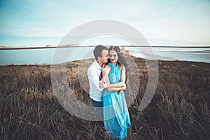 Young couple in love is resting together near the lake and mountains, beautiful caucasian woman and man fell in love