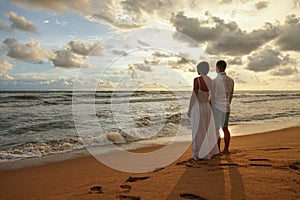 Young couple in love on a romantic date meets the sunset on the beach, holding hands