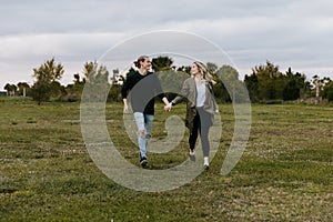 Young Couple in Love Running in a Big Open Outdoor Field in the Spring Holding Hands and Laughing