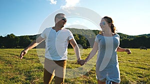 A young couple in love running through the field holding hands