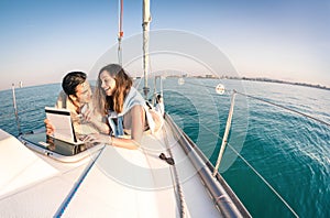 Young couple in love on sail boat having fun with tablet