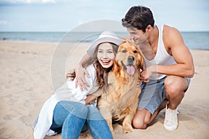 Young couple in love sitting on the beach with dog