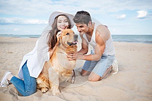 Young couple in love sitting on the beach with dog