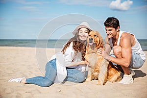 Young couple in love sitting on the beach with dog