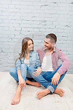 Young couple in love sitting on the floor and looking on each other