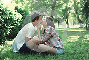 Young couple in love sitting on grass and kissing