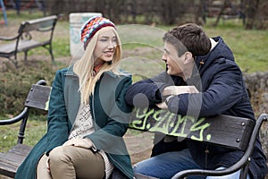 Young couple in love sitting together on the bench in the park