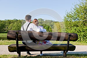 Young couple in love sitting together on a bench in park