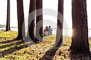 Young couple in love sitting under tree in the Park, enjoying a beautiful summer day at sunset.