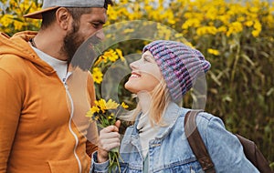 Young couple in love spends time together in autumn park with flovers. Man embracing and going to kiss sensual woman.