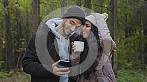 Young couple in love stand in embrace in nature drinking tea communicate enjoy romantic date happy tourists relaxing