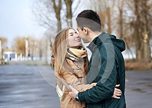 Young couple in love, standing, looking at each other, hugging, wearing casual clothes and jeans, on the rainy spring day.