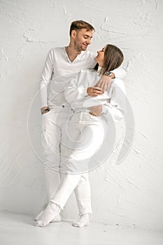 A young couple in love stands against the wall, looking at each other tenderly and lovingly.