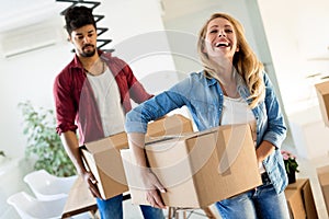 Young couple unpacking cardboard boxes at new home moving in concept