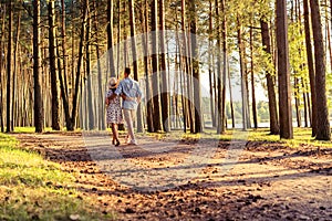 Young couple in love walking in the autumn park holding hands looking in the sunset.