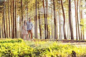 Young couple in love walking in the autumn park holding hands looking in the sunset.