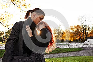 Young couple in love walking in the autumn park holding hands looking in the sunset