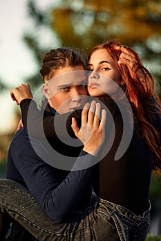 Young couple in love walking in the autumn park holding hands looking in the sunset