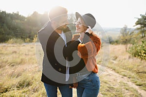 Young couple in love walking in the autumn park holding hands looking in the sunset.