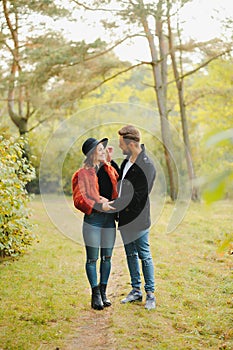 Young couple in love walking in the autumn park holding hands looking in the sunset.