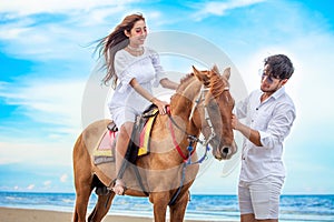 Young couple in love walking with the horse at sea beach on blue sky . honeymoon tropical sea summer vacation. bride groom on the