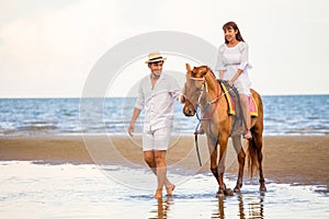 Young couple in love walking with the horse at sea beach on blue sky . honeymoon tropical sea summer vacation. bride groom on the