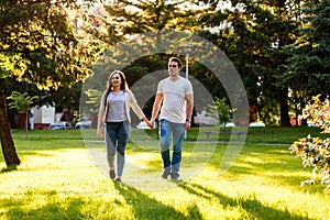 Young couple in love walking through meadow on sunny day